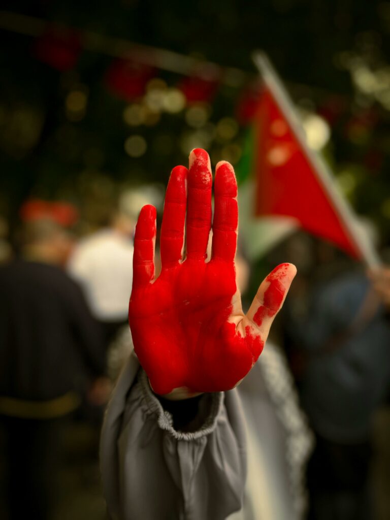 A protester raises a red painted hand during a rally in Gaza Strip, highlighting activism and resistance.