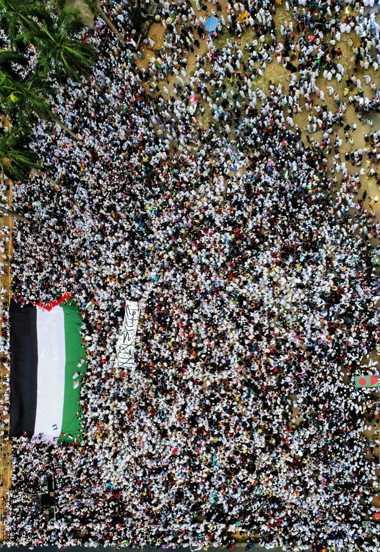 Aerial photo of a large crowd in Dhaka, Bangladesh, displaying a Palestinian flag.